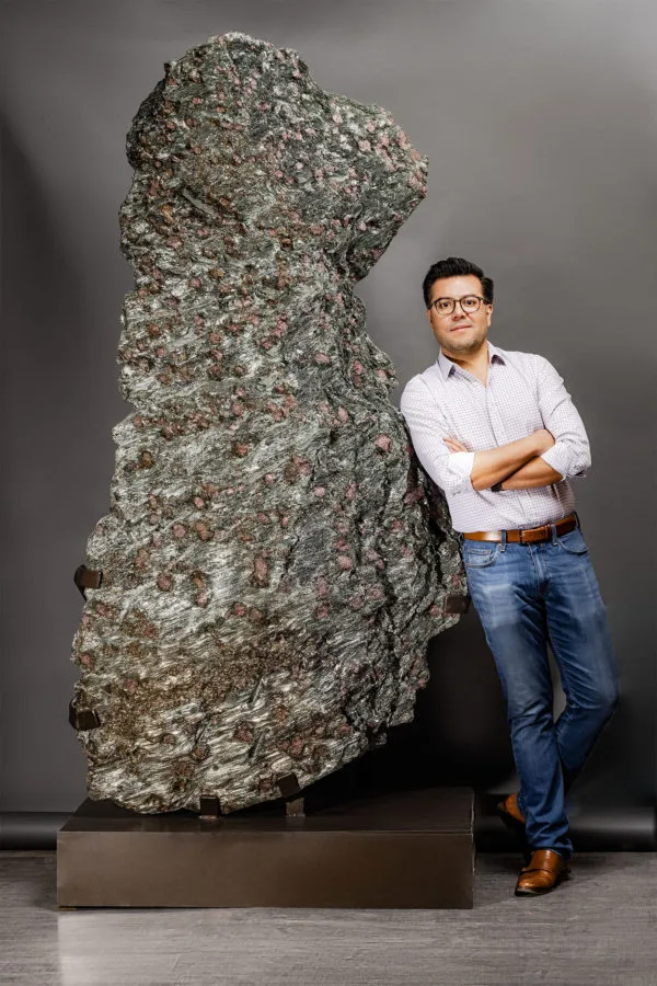 Ernesto Durán, founder of Pietra Gallery, beside a large mineral slab on a bronze plinth
